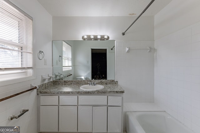 bathroom featuring vanity, tile walls, and tiled shower / bath