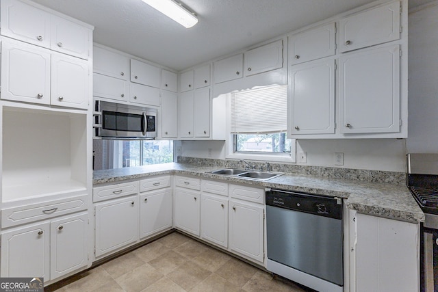 kitchen with appliances with stainless steel finishes, white cabinetry, sink, and a textured ceiling