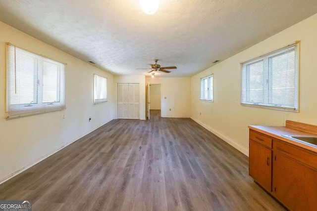 unfurnished living room with a textured ceiling, light wood-type flooring, ceiling fan, and sink