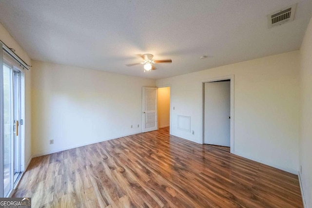 unfurnished bedroom featuring wood-type flooring, a textured ceiling, and ceiling fan