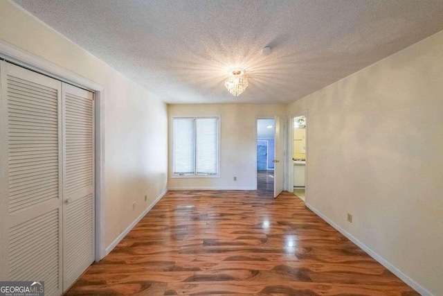 interior space featuring wood-type flooring, a textured ceiling, and an inviting chandelier