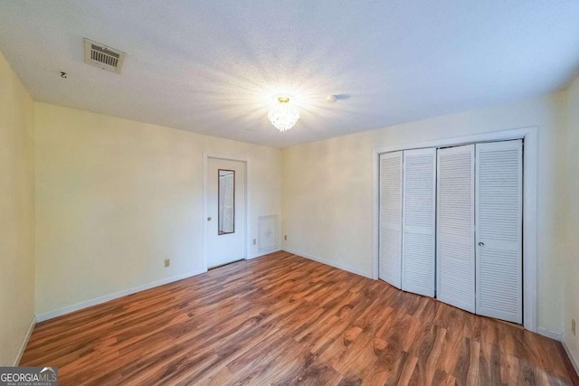 unfurnished bedroom with hardwood / wood-style flooring, a textured ceiling, and a closet