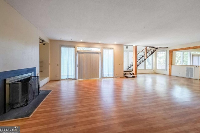 unfurnished living room with light hardwood / wood-style floors and a textured ceiling