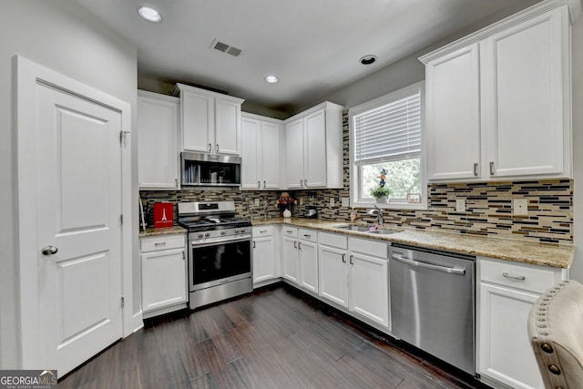 kitchen featuring light stone countertops, white cabinets, sink, dark hardwood / wood-style flooring, and appliances with stainless steel finishes