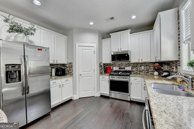 kitchen featuring light stone countertops, white cabinets, sink, dark hardwood / wood-style flooring, and appliances with stainless steel finishes