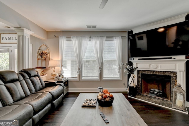 living room with a premium fireplace, decorative columns, and dark hardwood / wood-style floors