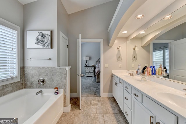 bathroom with lofted ceiling, vanity, and a bathing tub