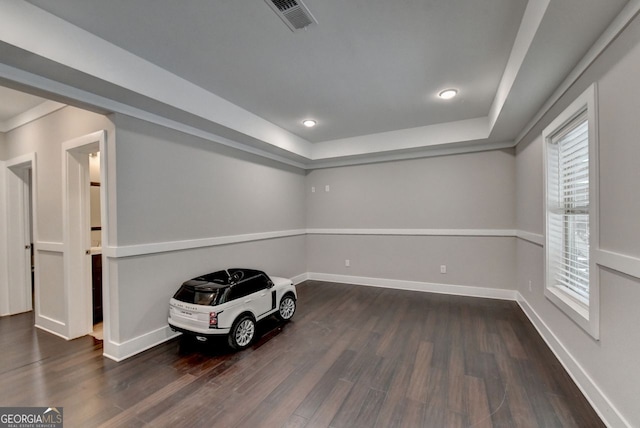 unfurnished room featuring a tray ceiling and dark hardwood / wood-style flooring