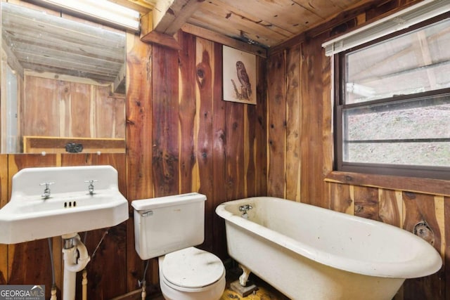 bathroom featuring wooden ceiling, a tub, wooden walls, and toilet