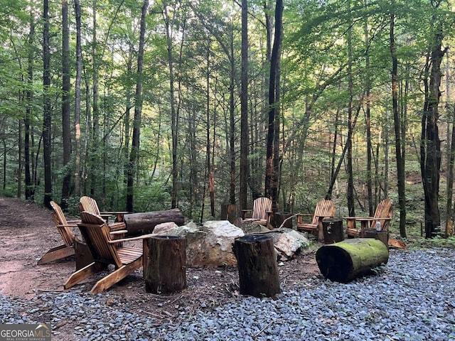 view of yard featuring an outdoor fire pit and a forest view