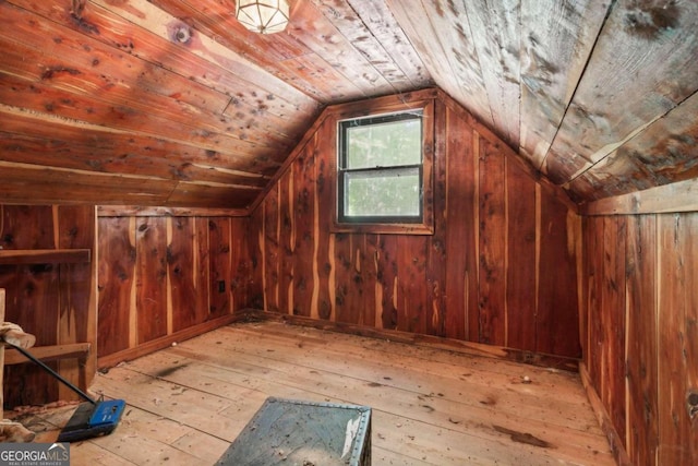 bonus room featuring wood walls, lofted ceiling, and light hardwood / wood-style flooring