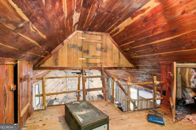 interior space featuring light wood-type flooring, wooden walls, and vaulted ceiling