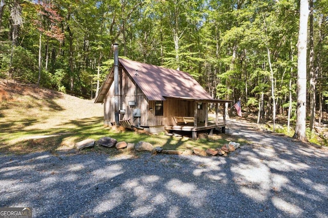 exterior space featuring a forest view, a chimney, and an outbuilding