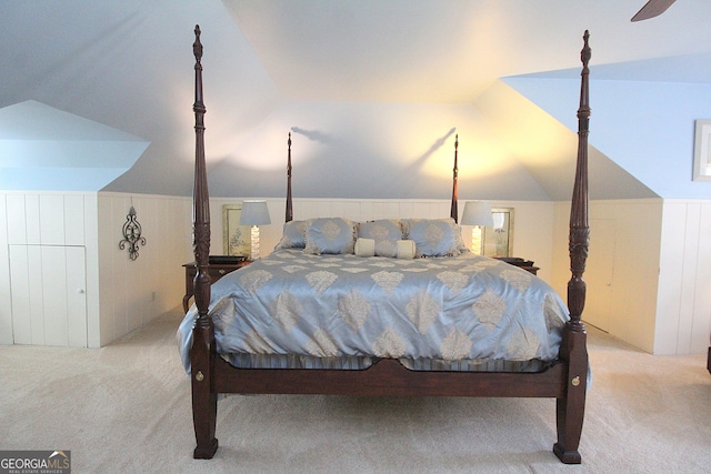 bedroom with wooden walls, vaulted ceiling, light colored carpet, and ceiling fan