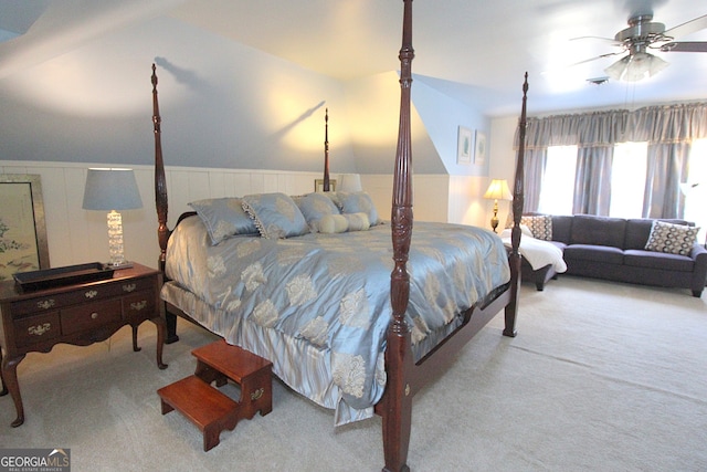 carpeted bedroom featuring wooden walls, vaulted ceiling, and ceiling fan