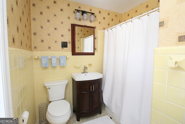 bathroom with tile walls, vanity, toilet, and a shower with shower curtain