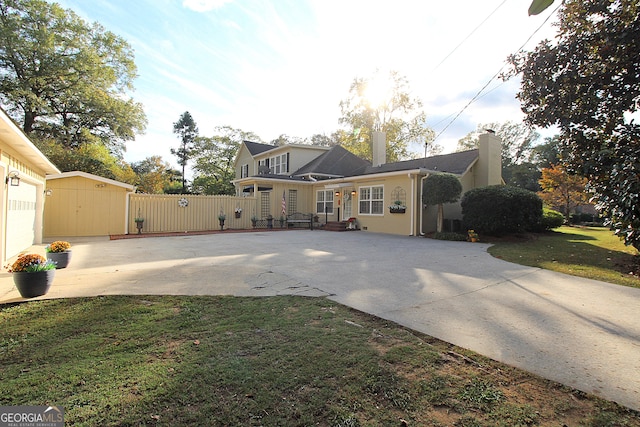 view of front of house featuring a front lawn and a storage shed