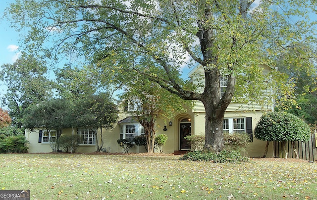 view of property hidden behind natural elements featuring a front lawn