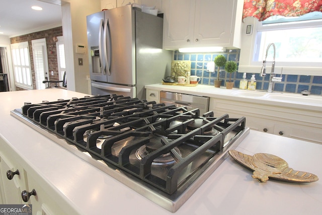 details featuring stainless steel appliances, white cabinetry, sink, and decorative backsplash