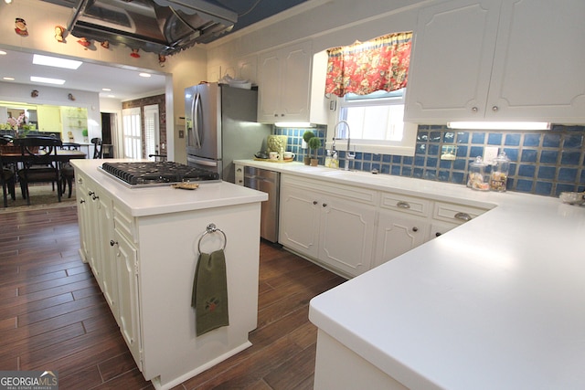 kitchen with dark hardwood / wood-style flooring, a center island, sink, tasteful backsplash, and appliances with stainless steel finishes