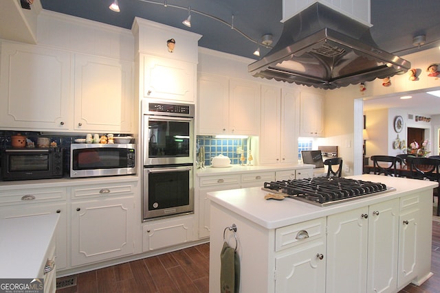 kitchen featuring ornamental molding, stainless steel appliances, a kitchen island, white cabinetry, and dark wood-type flooring