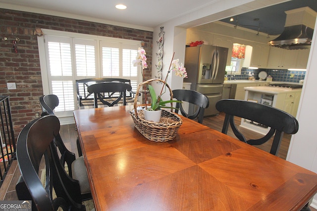 dining room with brick wall, hardwood / wood-style flooring, and crown molding