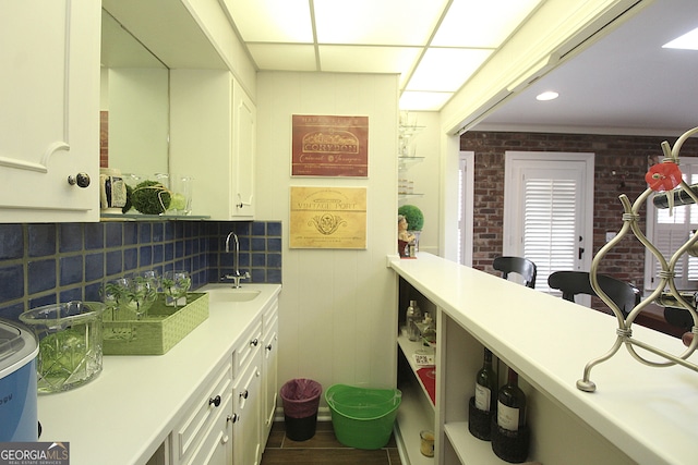 bathroom featuring tasteful backsplash, sink, and brick wall