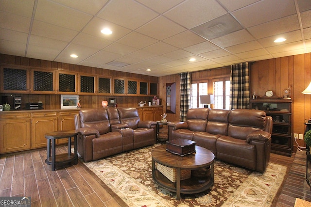 living room with wood walls, dark hardwood / wood-style floors, and a paneled ceiling