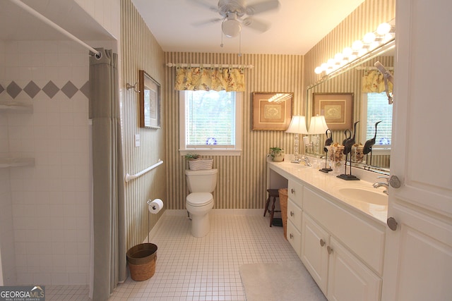 bathroom with ceiling fan, a tile shower, vanity, tile patterned floors, and toilet