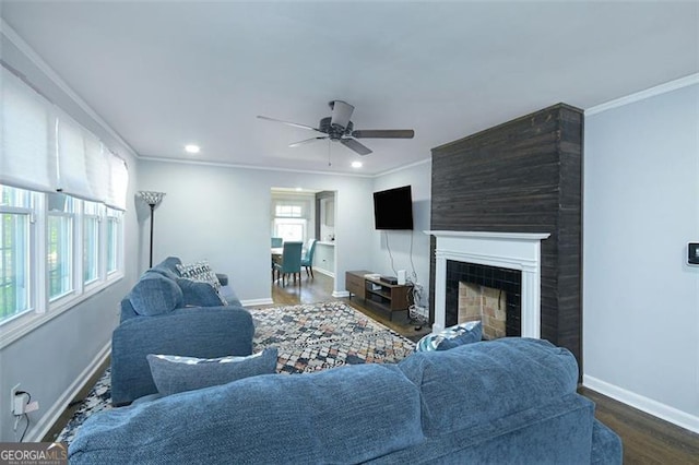 living room featuring a tile fireplace, ornamental molding, ceiling fan, and dark wood-type flooring