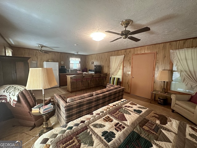 living room featuring ceiling fan, a textured ceiling, and wood walls