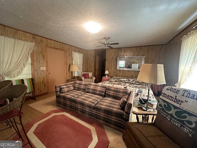 living room featuring wooden walls, ceiling fan, and a textured ceiling