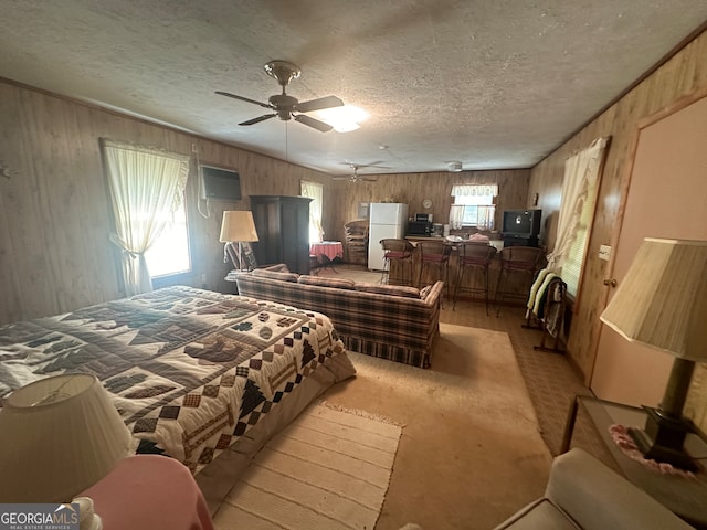 bedroom with ceiling fan, white fridge, multiple windows, and light carpet