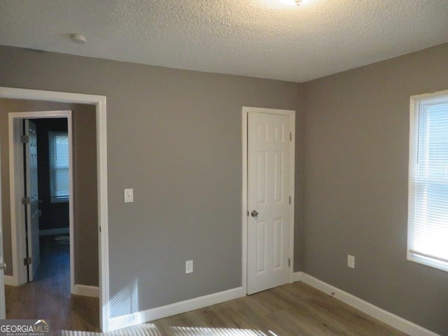empty room with baseboards, wood finished floors, and a textured ceiling