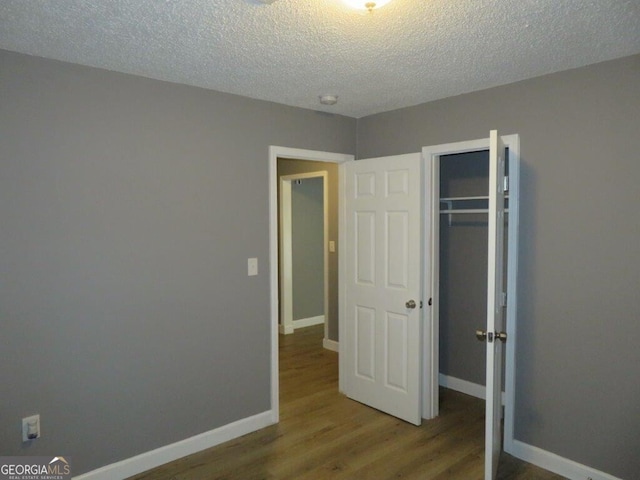 unfurnished bedroom featuring a textured ceiling, a closet, and hardwood / wood-style floors