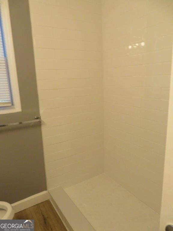 full bathroom featuring baseboards, walk in shower, and wood finished floors