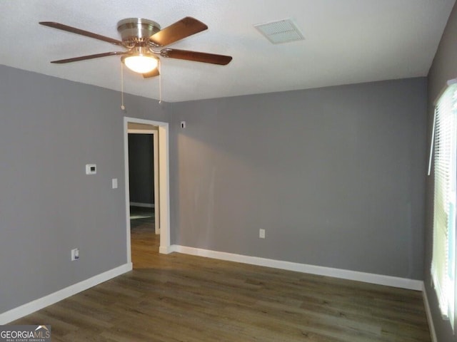 empty room with ceiling fan, baseboards, wood finished floors, and visible vents