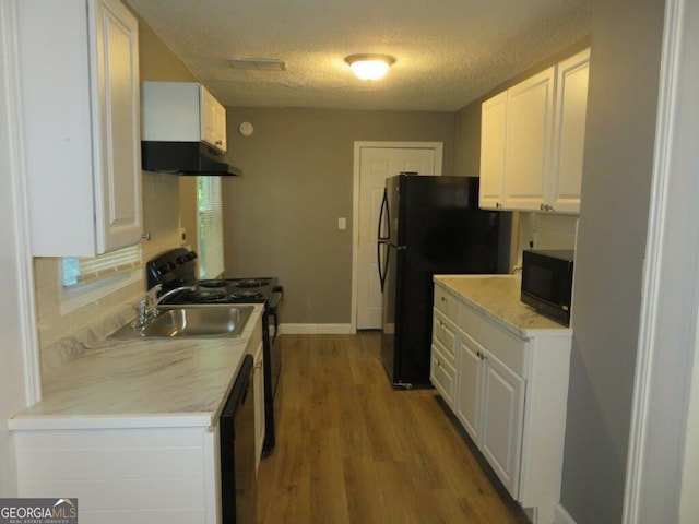 kitchen with a textured ceiling, black appliances, light wood finished floors, white cabinets, and under cabinet range hood