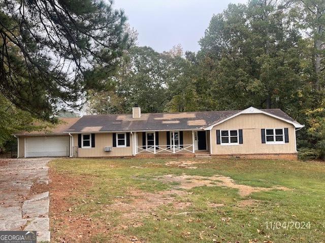 ranch-style home with a front lawn, a porch, and a garage