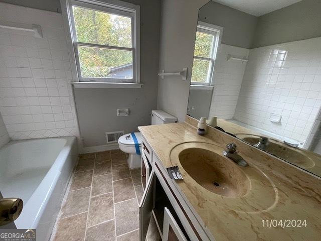 bathroom featuring a bath, vanity, toilet, and tile patterned floors