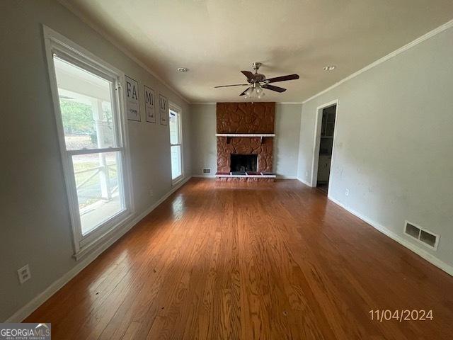 unfurnished living room with a fireplace, hardwood / wood-style flooring, ceiling fan, and a healthy amount of sunlight