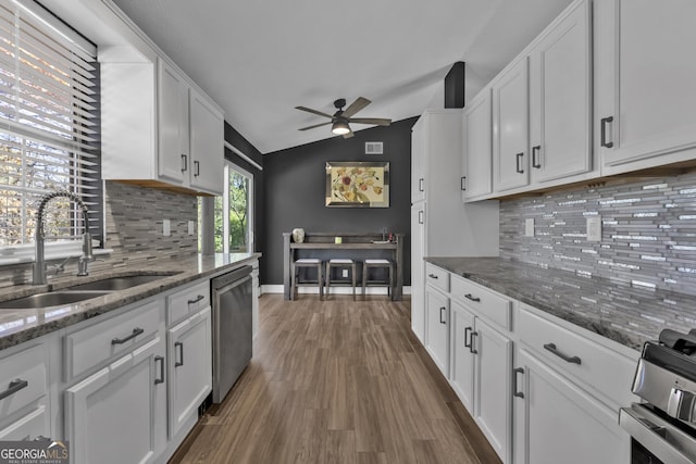 kitchen with white cabinetry, sink, stainless steel appliances, and vaulted ceiling