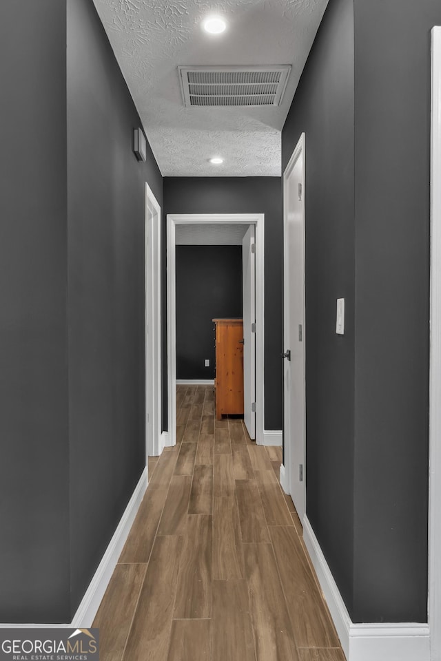 hall featuring hardwood / wood-style floors and a textured ceiling