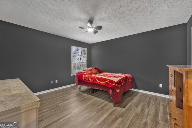 bedroom featuring a textured ceiling, dark hardwood / wood-style floors, and ceiling fan