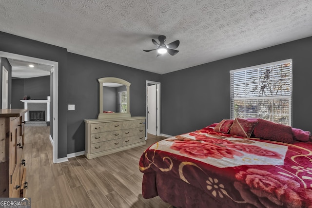 bedroom featuring a textured ceiling, light hardwood / wood-style flooring, and ceiling fan