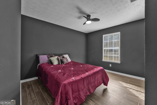 bedroom featuring a textured ceiling, ceiling fan, and dark hardwood / wood-style floors