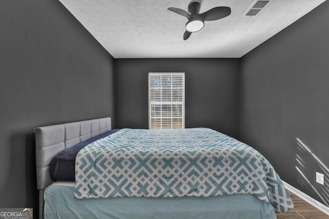 bedroom featuring ceiling fan, wood-type flooring, and a textured ceiling