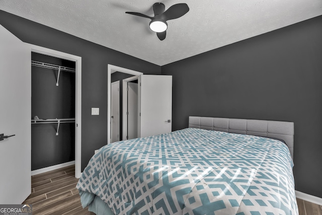 bedroom with ceiling fan, dark wood-type flooring, and a textured ceiling