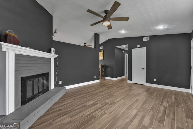 unfurnished living room featuring ceiling fan, high vaulted ceiling, wood-type flooring, a textured ceiling, and a fireplace