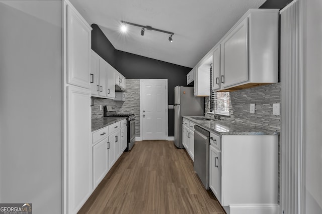 kitchen with white cabinets, stainless steel appliances, stone counters, and sink